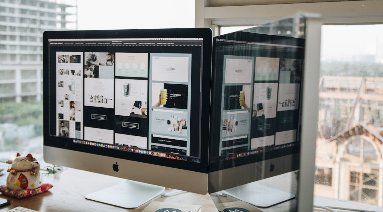 services-03 Dual monitors on a desk, showcasing web design in a modern office setting.